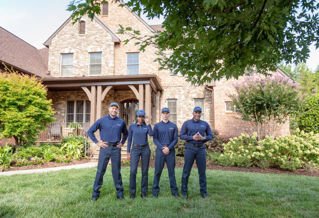 4 members of the Rocket Pest Control team standing in front of a Southeastern US home